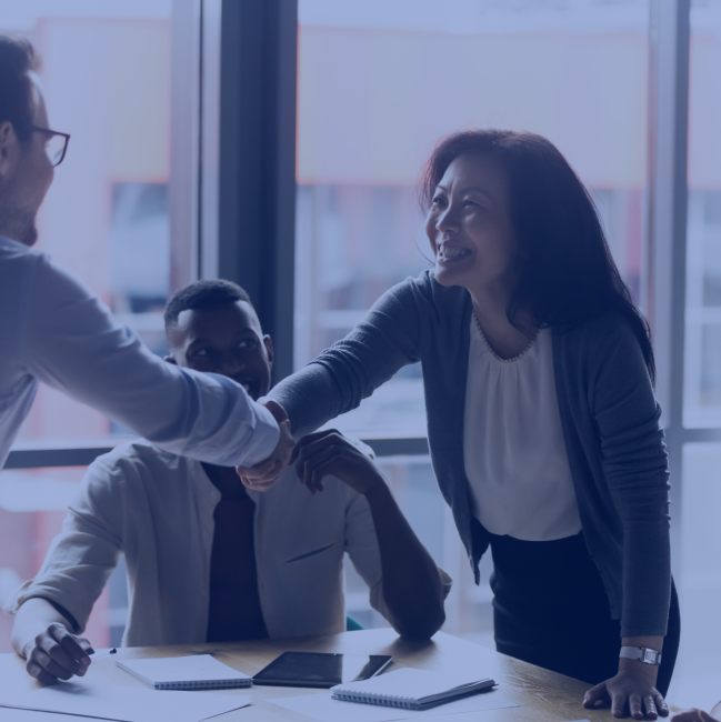 Asian American woman shakes hands with a man, closing a business deal or partnership.